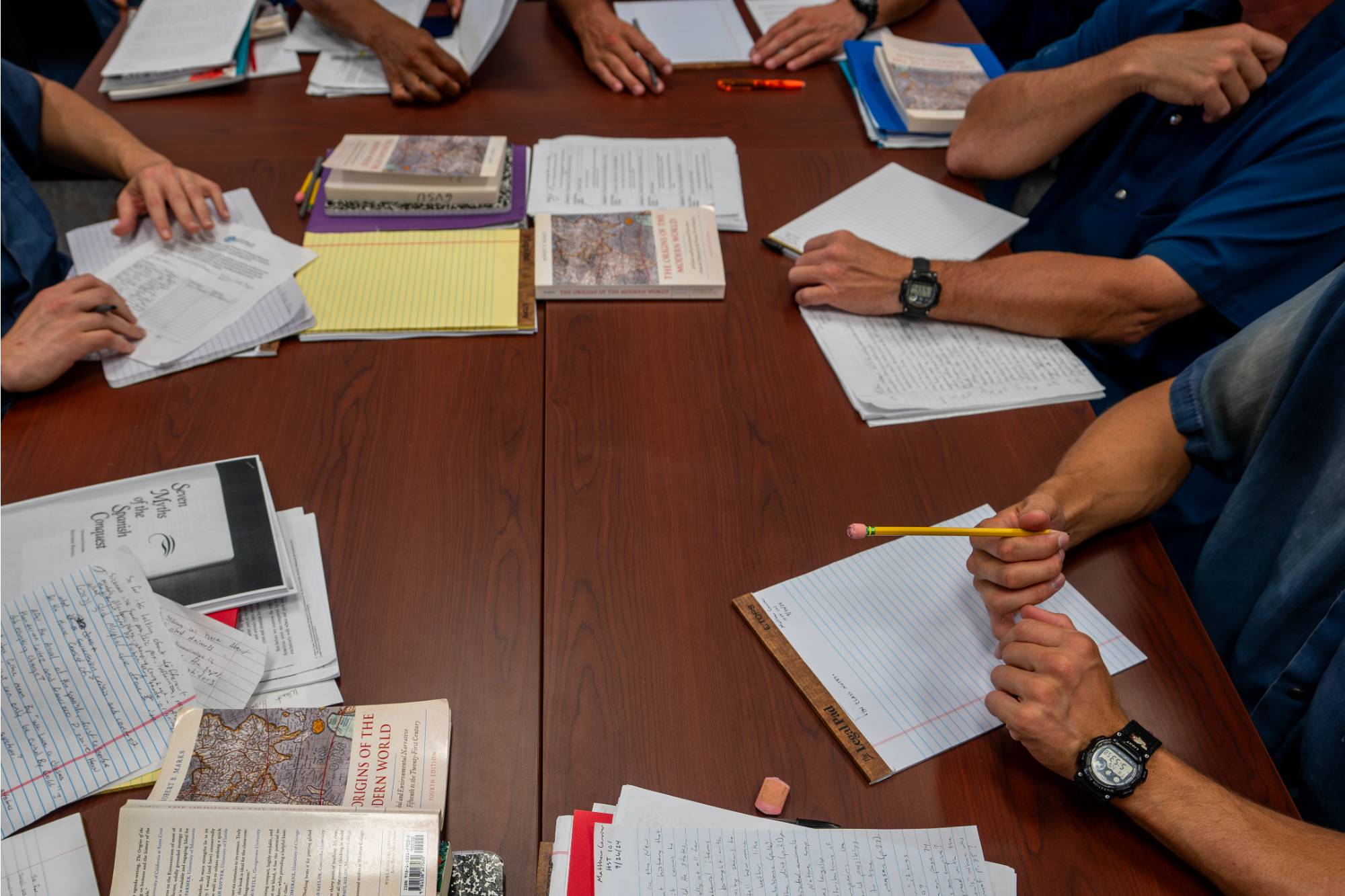 Desk in classroom, covered with course papers and books